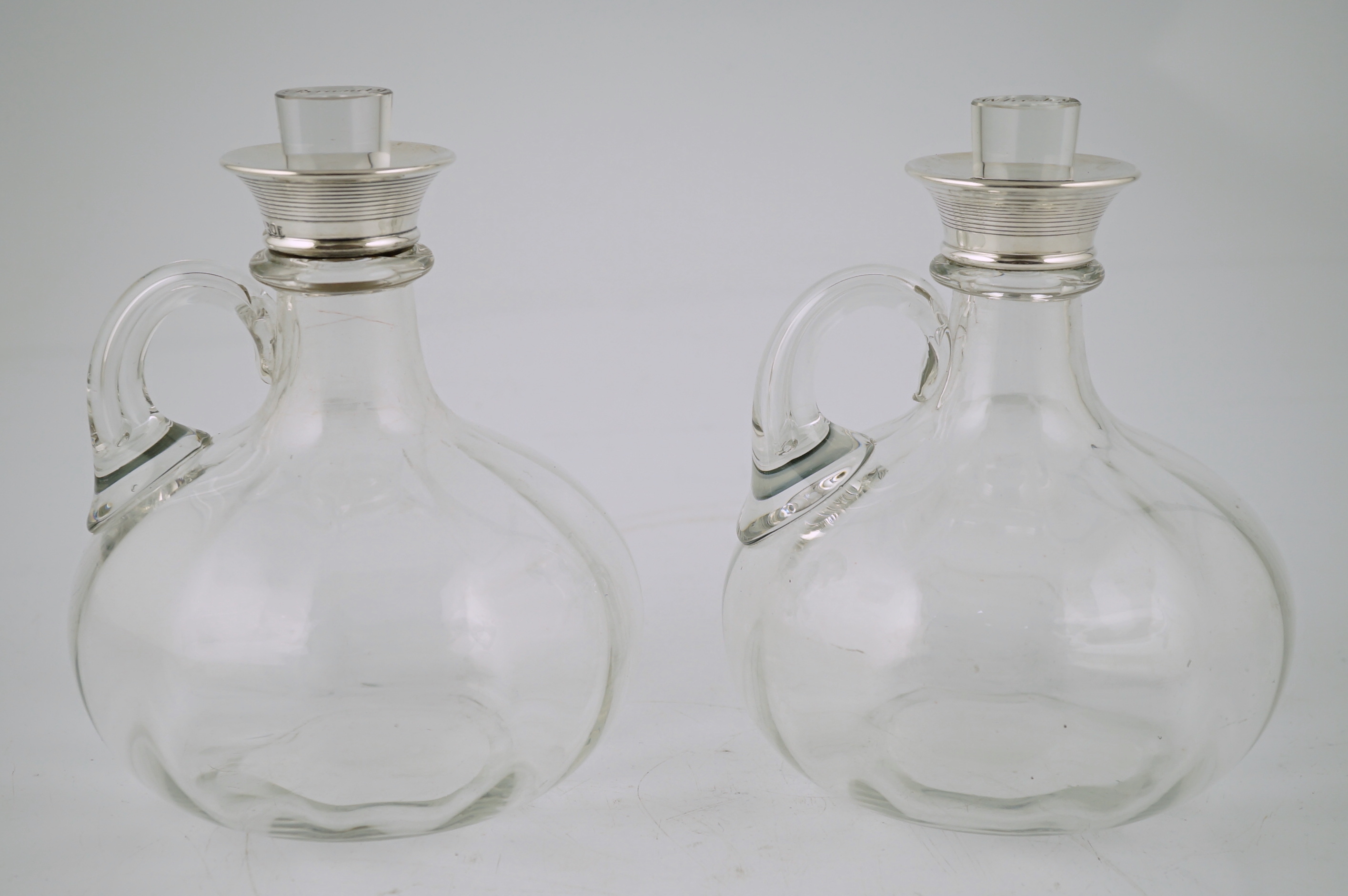 A pair of Edwardian silver mounted glass decanters, with stoppers etched 'Whisky' & 'Brandy', by Charles & George Asprey